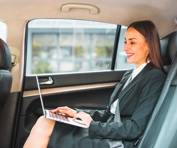Auto con Autista Milano: sorridente imprenditrice con pc portatile dentro la macchina