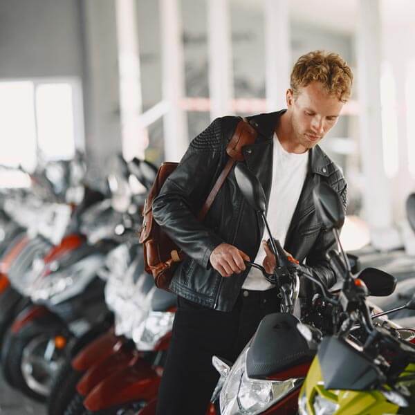 Noleggio Auto con Conducente Milano: ragazzo con una giacca nera guarda le motociclette nel'EICMA